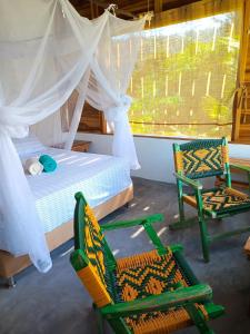 a bedroom with two chairs and a bed and a window at Frana Lodge in El Zaino