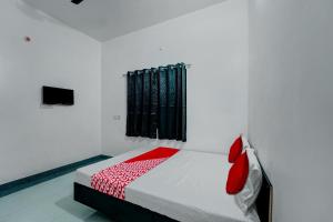 una camera da letto con un letto con cuscini rossi e una finestra di As Hotels & Banquet a Hazārībāg