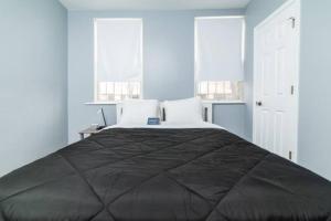 a bedroom with a large black bed with two windows at 1st Floor - Free Parking - Washer & Dryer - AGH in Pittsburgh