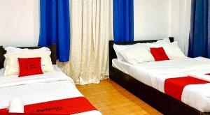 two beds in a room with blue and red pillows at RedDoorz @ Nena's Hotel Dagupan City in Dagupan