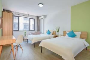 a hotel room with two beds and a desk at DuoDuo Hotel Apartment - Yiwu International Trade City in Yiwu
