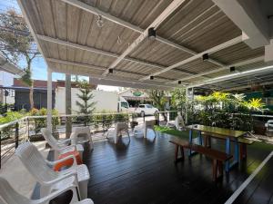 a patio with white chairs and tables and a wooden deck at Nautical Home & Seashell House B&B in Khao Lak
