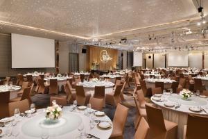 a conference room with tables and chairs and a projection screen at Le Meridien Taipei in Taipei