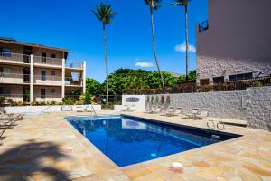 a swimming pool at a hotel with palm trees at Charming Loft 2BR with Free Parking & Near Beach! in Kihei