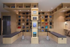 uma biblioteca com dois bancos e prateleiras com livros em Hangzhou Desti Youth Park Hostel em Hangzhou