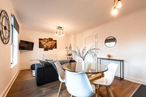 een eetkamer en een woonkamer met een glazen tafel en witte stoelen bij Marigold- 2 Bedroom, Sleeps 5 in Southampton