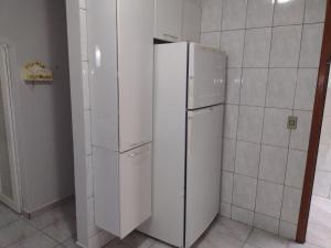 a white refrigerator in a kitchen with white tiles at Casa Caraguá in Caraguatatuba