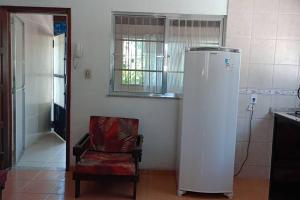 - une cuisine avec une chaise et un réfrigérateur dans la chambre dans l'établissement Casa de praia Pitória São Pedro da Aldeia, à São Pedro da Aldeia