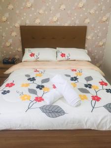 a bed with a white blanket with flowers on it at Brenthill Condominium in Baguio