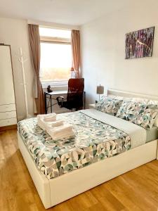 1 dormitorio con 1 cama con silla y ventana en Paddington Flat Close to Station with Patio en Londres