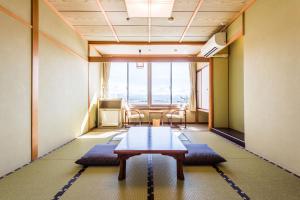 Zimmer mit einem Tisch und Stühlen sowie einem großen Fenster in der Unterkunft Ooedo Onsen Monogatari Nagayama in Kaga