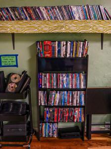 a book shelf filled with dvds next to a stack of movies at Treasure State Hostel in Bozeman