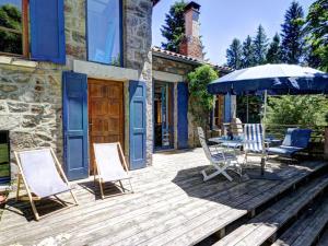 a patio with a table and chairs and an umbrella at Chalet familial spacieux avec sauna au cœur du Parc du Pilat - FR-1-496-24 in Le Bessat