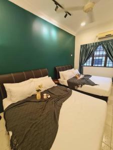 two beds in a bedroom with a green wall at Pleasant Stay @ Sunway (16-20 pax ) 5 min to Lost World of Tambun in Tambun