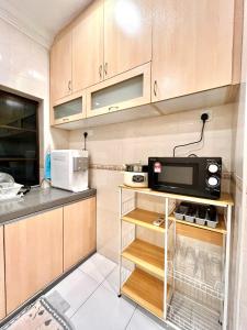 a kitchen with wooden cabinets and a microwave at Pleasant Stay @ Sunway (16-20 pax ) 5 min to Lost World of Tambun in Tambun