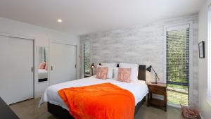 a bedroom with a large bed with an orange blanket at Mapua41South in Mapua