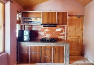 a small kitchen with wooden cabinets and a microwave at The Naggar Trails in Nagar