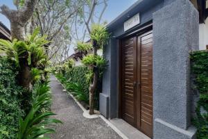 un bâtiment bleu avec une porte marron et quelques plantes dans l'établissement Alam Bidadari Seminyak, à Seminyak