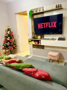 uma cama num quarto com televisão e uma árvore de Natal em Apê 104-B Confortável no Centro em Foz do Iguaçu