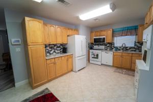 eine große Küche mit Holzschränken und weißen Geräten in der Unterkunft Bacolet Beach Luxe Pool Cottage in Palm Beach Gardens