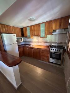 eine Küche mit Holzschränken und einem weißen Kühlschrank in der Unterkunft Casa Quinta en Gonnet in Manuel B. Gonnet