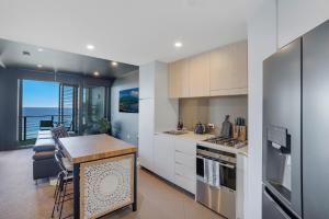 a kitchen with white cabinets and a view of the ocean at 703 Luxury Ocean View Apartment in Newcastle