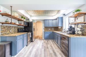 una cocina azul con suelo de madera y armarios azules en Relaxing Modern Farmhouse in Jupiter Farms. Family-and Dog-friendly!, en Jupiter