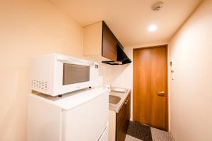 a small kitchen with a microwave on top of a refrigerator at HOTEL THE POINT Kiyomizu Gojo in Kyoto