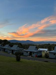 a group of houses with a sunset in the background at Alpine Village Jindabyne in Jindabyne