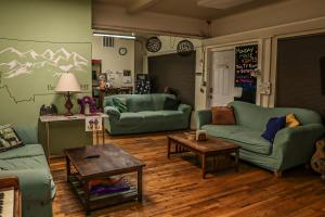 a living room with green couches and a table at Treasure State Hostel in Bozeman