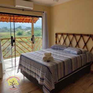 a bedroom with a bed and a large window at Pousada Camping dos Ypês in Guapimirim