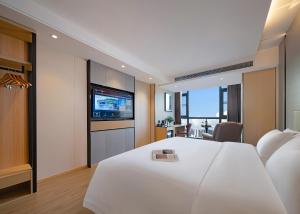Pokój hotelowy z białym łóżkiem i telewizorem w obiekcie Zhangjiajie Hero Boutique Hotel w mieście Zhangjiajie