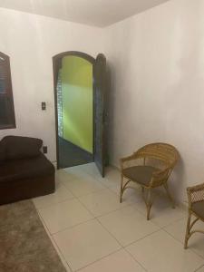 a living room with a door and a couch and chair at Casa Em condomínio portaria24 horas,piscina in Cabo Frio