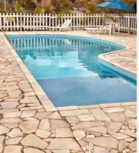 einen Pool mit blauem Wasser und einem weißen Zaun in der Unterkunft Casa Em condomínio portaria24 horas,piscina in Cabo Frio