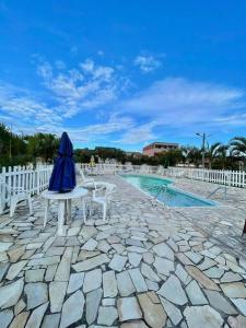 eine Terrasse mit 2 Stühlen und einem blauen Sonnenschirm in der Unterkunft Casa Em condomínio portaria24 horas,piscina in Cabo Frio