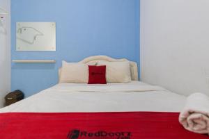 een slaapkamer met een wit bed en een rood kussen bij RedDoorz @ Garden Boulevard Citra Raya Tangerang in Tangerang