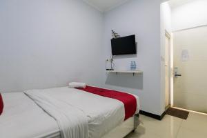 a white bedroom with a bed and a flat screen tv at RedDoorz @ Garden Boulevard Citra Raya Tangerang in Tangerang