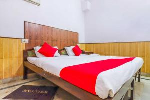 - une chambre dotée d'un grand lit avec des oreillers rouges et blancs dans l'établissement Flagship Hotel Prem Chunaria, à Moradabad