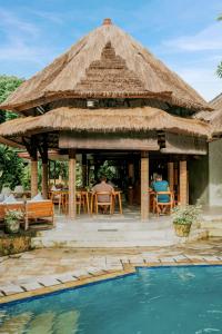 サヌールにあるスリ ファラ リゾート & ヴィラのテーブル席とプール付きの大きな小屋