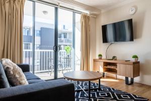 a living room with a couch and a tv at Urban Luxury City Apartment with Pool and Parking in Brisbane