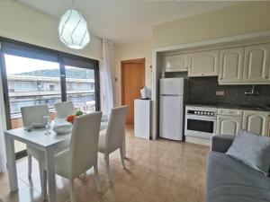 a kitchen and dining room with a table and chairs and a kitchen with white appliances at Apartamento en el Centro de Platja d'Aro con Piscina, Terraza y Cerca de la Playa - ES-209-45 in Platja  d'Aro