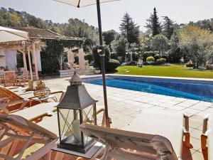 een patio met stoelen en een parasol naast een zwembad bij Casa Caldes de Malavella, 5 dormitorios, 10 personas - ES-209-37 in Caldes de Malavella