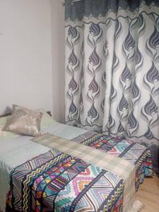 a bed with a comforter and curtains in a room at PagersHome Suites- RUSTIC in Kigali