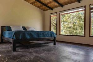 1 dormitorio con 1 cama y 2 ventanas en Riverside Cabin in Cumandá, near Baños, Ecuador, en Mera