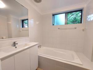 a white bathroom with a tub and a sink at Eastwood Furnished Apartments in Sydney
