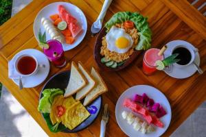 a wooden table with plates of breakfast foods and coffee at Adi Guest house in Blongas