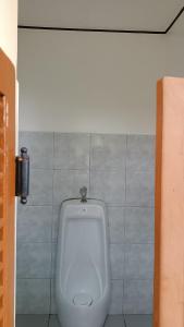 a white urinal in a bathroom with a tile wall at Loony Cafe & Guesthouse in Loon