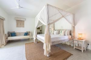 a bedroom with a canopy bed and a couch at Hibiscus Home&Apartments in Galu