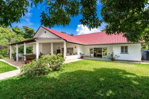 a house with a red roof and a yard at Hibiscus in Diani Beach