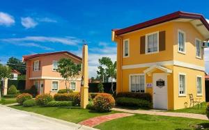 a yellow house with a white door in a yard at Camella homes laoag city ilocos norte in Bangued